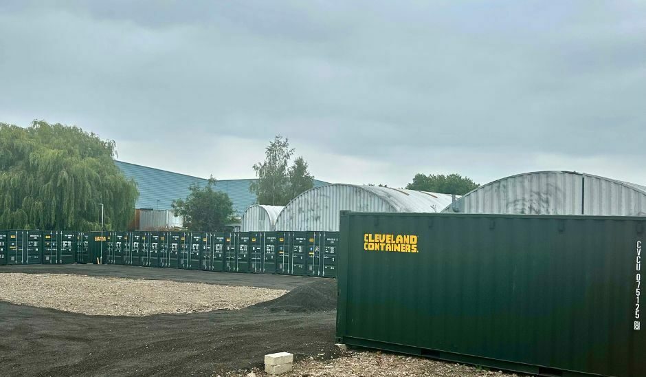 Storage yard with green containers and gravel ground